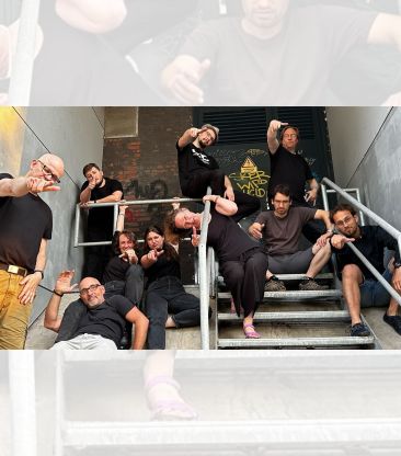 die improtheater-gruppe eukalyptussalat auf treppen, es sind 10 leute, dunkel gekleidet in verschiedenen posen
